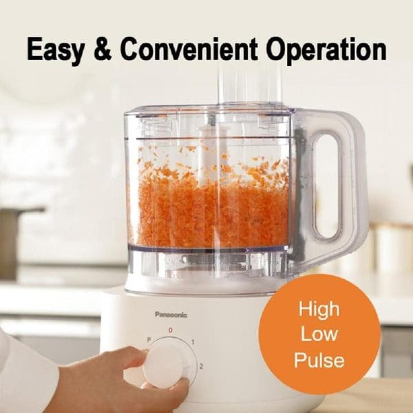 Panasonic MK-F310 food processor with clear bowl containing chopped orange ingredients, hand adjusting control dial, featuring High/Low/Pulse settings for easy kitchen operation.