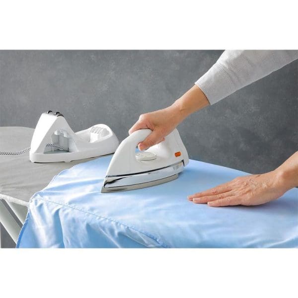 Person using white Panasonic NI-100DX cordless iron with non-stick soleplate on blue fabric, showing 1000W appliance with charging base on ironing board.