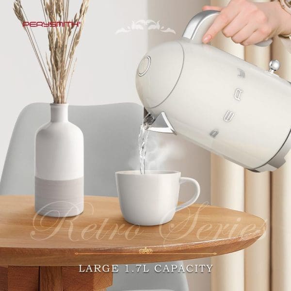 PerySmith KT1010 Retro Series Electric Kettle in cream color with 1.7L capacity pouring hot water into white mug on wooden table with decorative vase.