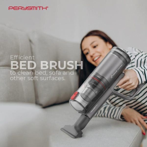 Woman using PerySmith Xtreme Series X10 Pro handheld vacuum cleaner on white sofa, demonstrating efficient bed brush attachment for cleaning soft surfaces.