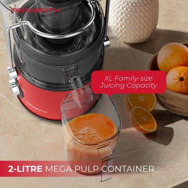 PerySmith red and black juice extractor with 2-litre pulp container, extracting orange juice from fresh oranges on kitchen counter with pineapple in background.