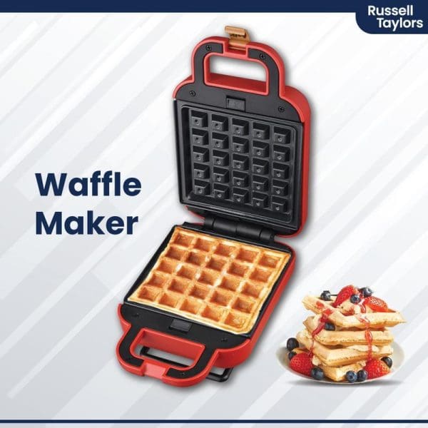 Russell Taylors red and black waffle maker open showing cooked waffle inside, with stack of waffles topped with berries on white background.