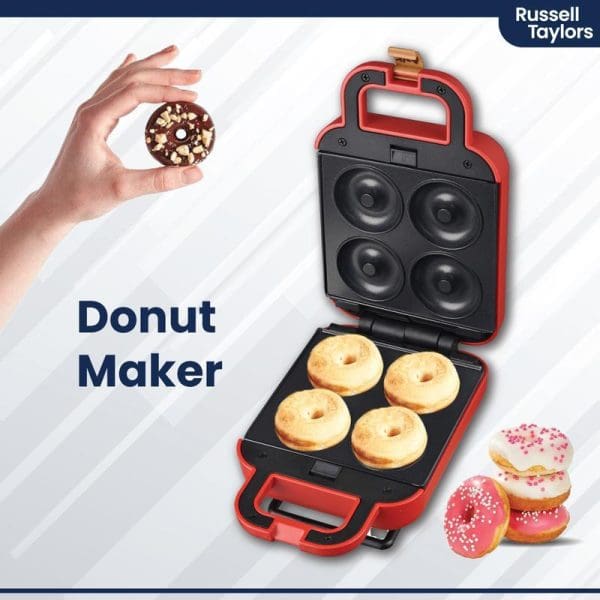Russell Taylors red and black donut maker with open lid showing four golden donuts inside, hand holding chocolate donut, decorated donuts nearby.