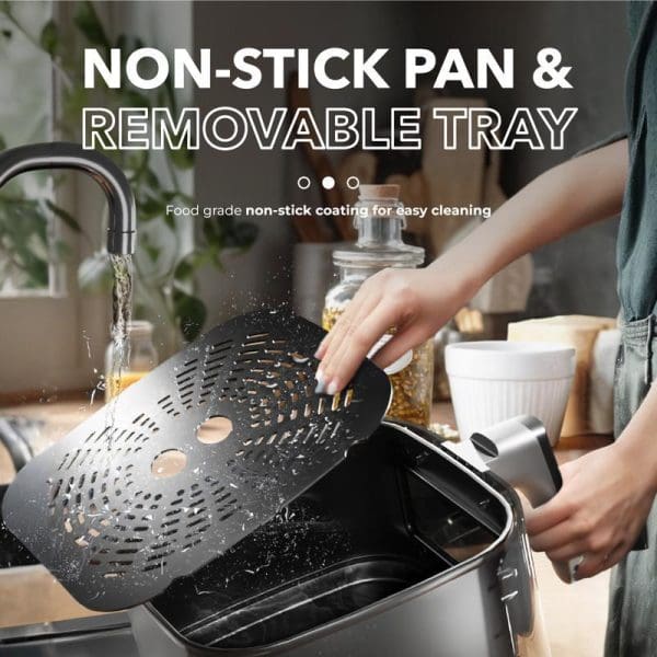 Person washing black perforated removable tray from Russell Taylors 3D Visionary Digital Air Fryer under running water, demonstrating non-stick coating and easy cleaning features.