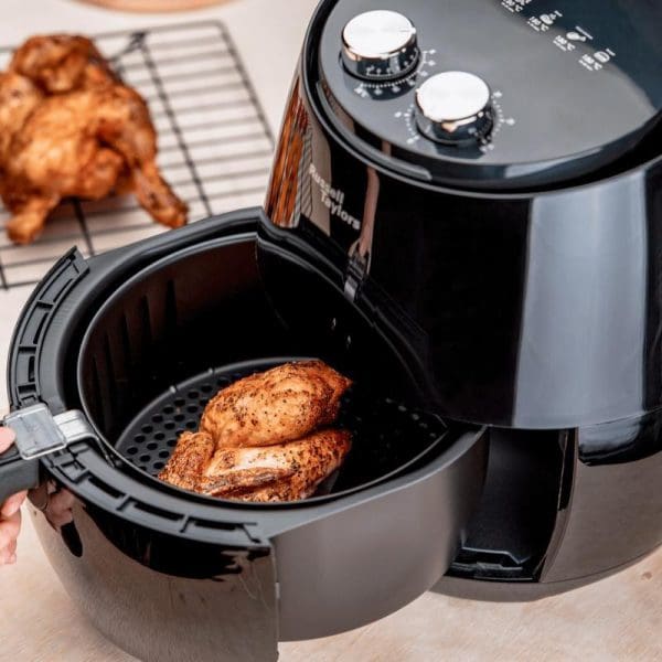 Russell Taylors Air Fryer XL (4.8L) AF-34 with open basket containing seasoned chicken pieces, cooked chicken on cooling rack in background.