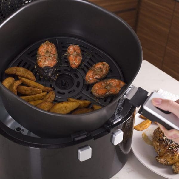 Russell Taylors Digital Rotary Air Fryer AF-76 7.5L cooking potato wedges and seasoned chicken pieces with cooked food on nearby plate.