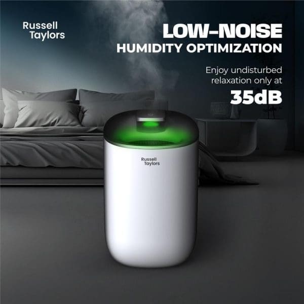 Russell Taylors white portable dehumidifier with green LED light and 600ml water tank in bedroom setting, highlighting 35dB low-noise operation for quiet humidity optimization.