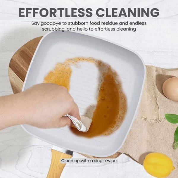 Hand wiping clean a white marble non-stick pan with cooked egg residue using a cloth, demonstrating effortless cleaning capabilities of cookware.