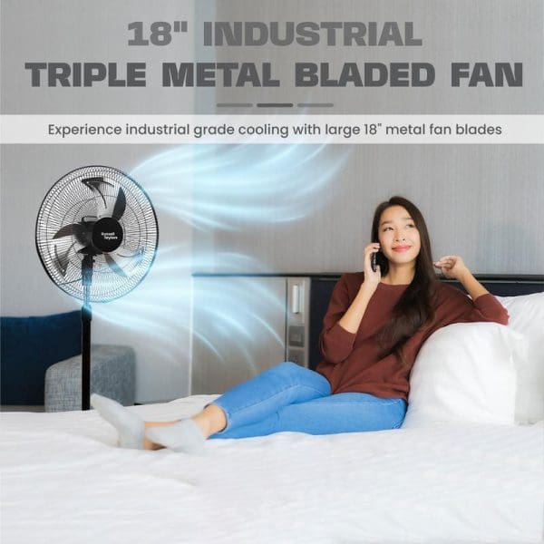 Russell Taylors 18-inch industrial triple metal bladed stand fan with woman relaxing on bed talking on phone, showing cooling airflow effect.