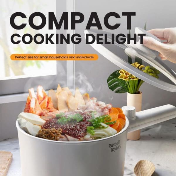 Russell Taylors 1.5L white electric multi cooker with glass lid, containing colorful hot pot ingredients including vegetables, meat, and noodles on kitchen counter.