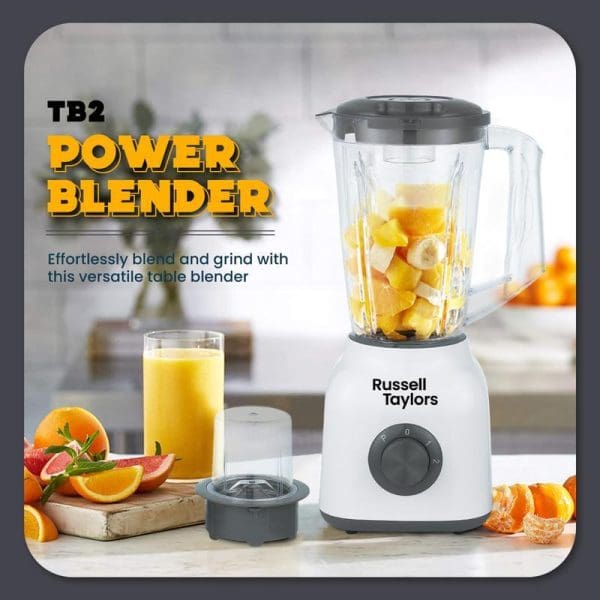 Russell Taylors TB2 Power Blender with 1.5L glass jug and dry mill attachment, featuring white base with control dial, surrounded by fresh fruits and orange juice.