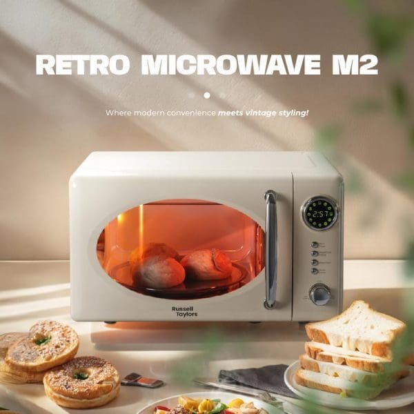 Russell Taylors Retro Microwave M2 20L in cream color with digital display, orange interior lighting, surrounded by donuts and bread on kitchen counter.