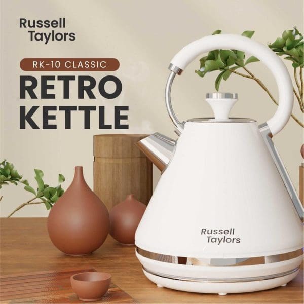 Russell Taylors RK-10 Classic white retro electric kettle with stainless steel accents on wooden counter with terracotta vases and green plants in background.
