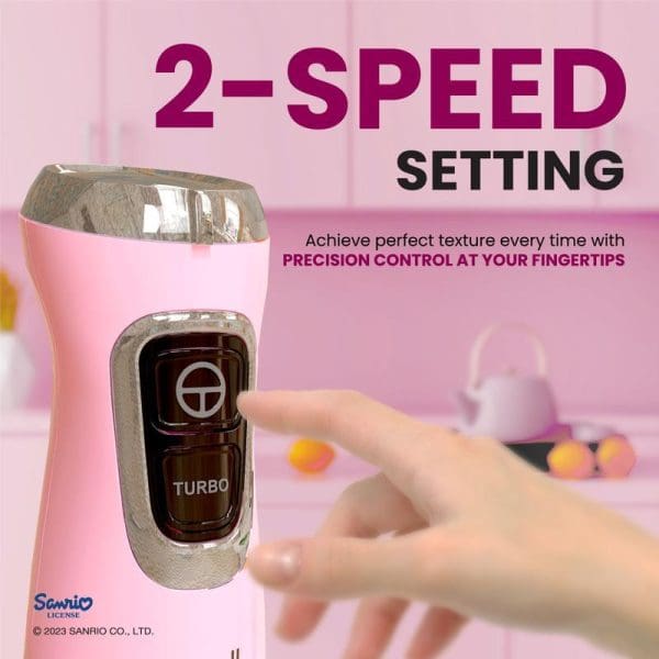 Pink Hello Kitty hand blender featuring 2-speed turbo setting with precision control, shown with hand demonstrating button operation in kitchen setting.