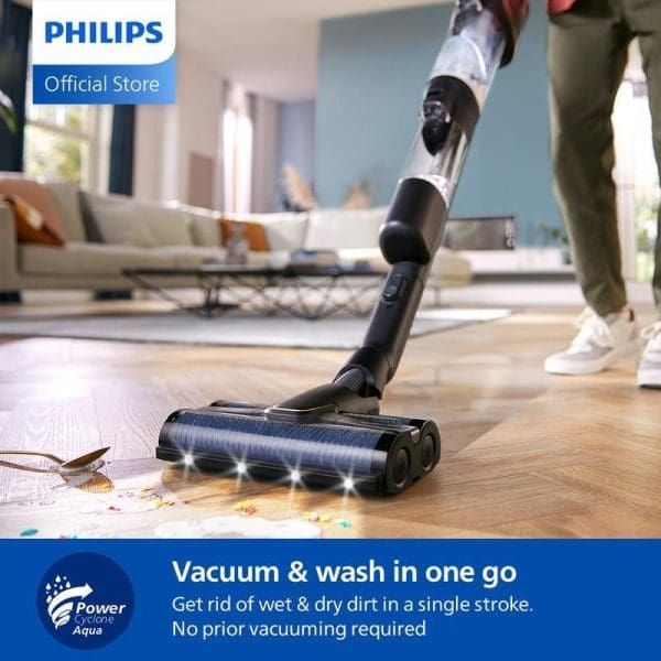 Philips XW9465 Pembersih Vakum Tanpa Wayar 3-in-1 Basah dan Kering sedang membersihkan serpihan makanan di atas lantai kayu dalam ruang tamu moden.